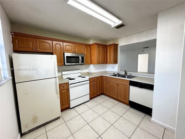 kitchen featuring sink, light tile patterned floors, a textured ceiling, and white appliances