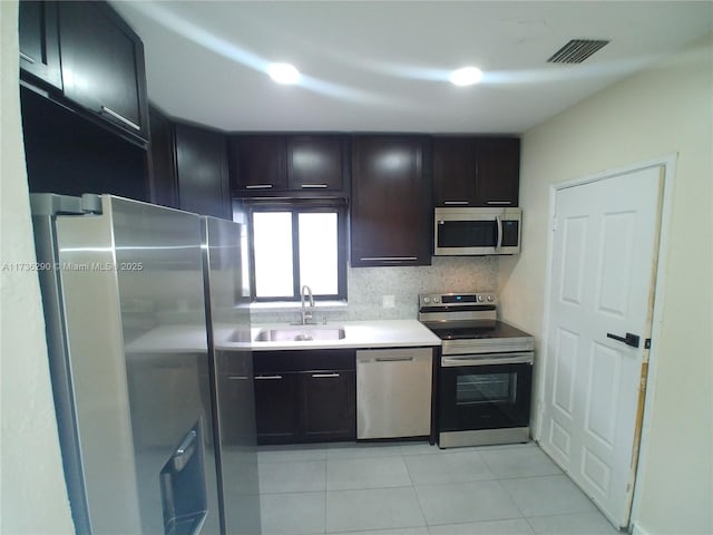 kitchen featuring light tile patterned floors, stainless steel appliances, sink, and backsplash