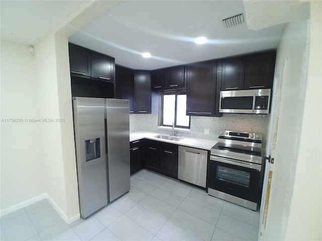 kitchen with appliances with stainless steel finishes, sink, light tile patterned floors, and backsplash