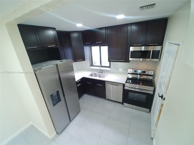 kitchen with appliances with stainless steel finishes, sink, decorative backsplash, and light tile patterned floors