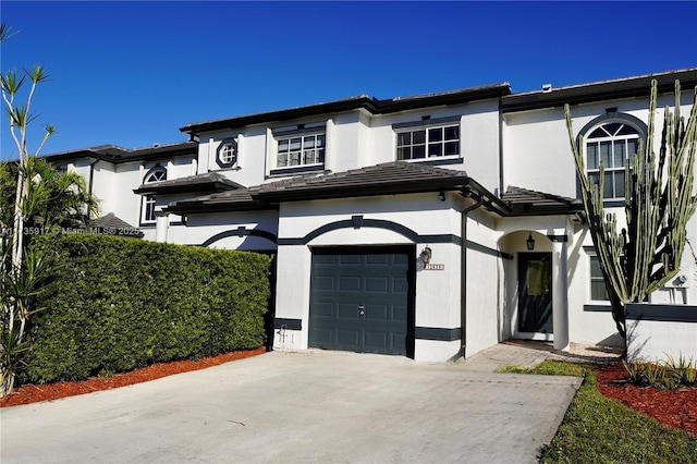 view of front of house with driveway, an attached garage, and stucco siding