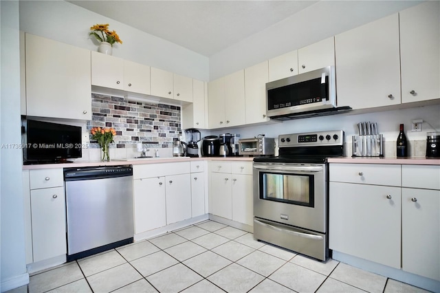 kitchen with light tile patterned floors, backsplash, stainless steel appliances, light countertops, and a sink