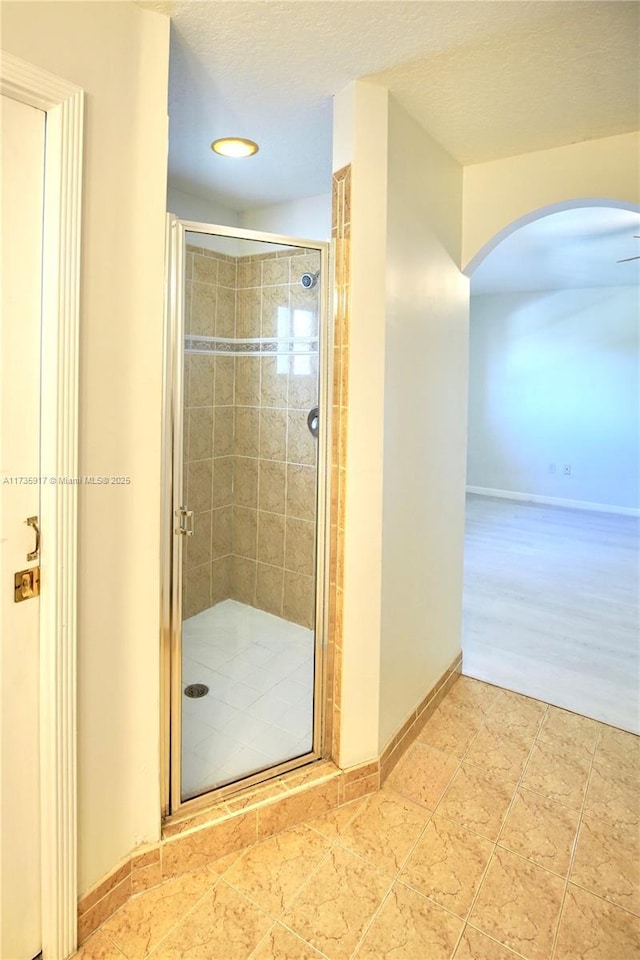 full bathroom featuring a shower stall, baseboards, and a textured ceiling