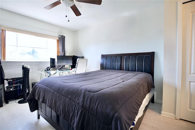 bedroom featuring light wood finished floors, a ceiling fan, and baseboards