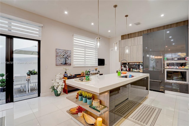 kitchen with modern cabinets, light countertops, stainless steel oven, a sink, and light tile patterned flooring