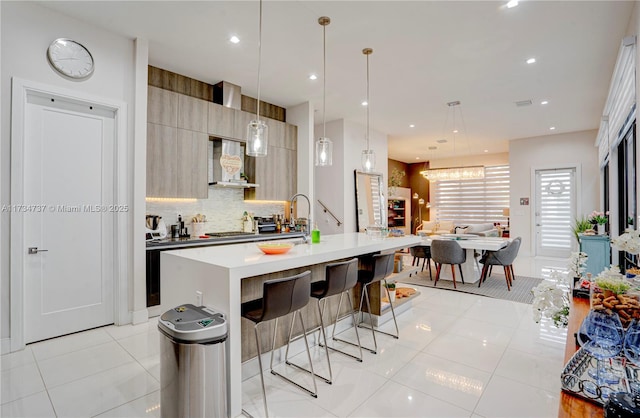 kitchen with light tile patterned flooring, a breakfast bar, wall chimney range hood, decorative backsplash, and modern cabinets