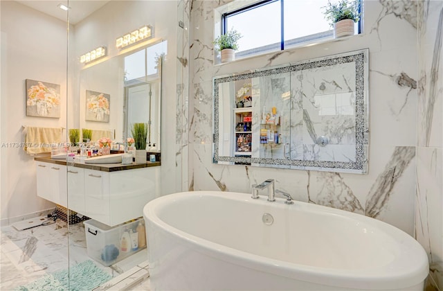 bathroom with marble finish floor, a freestanding tub, tile walls, and vanity