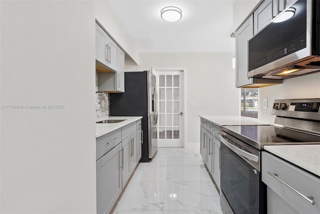 kitchen featuring appliances with stainless steel finishes, sink, gray cabinetry, and decorative backsplash