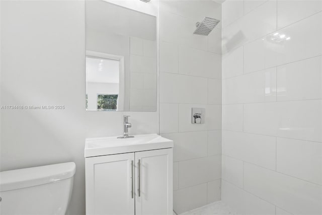 bathroom with vanity, tiled shower, and toilet