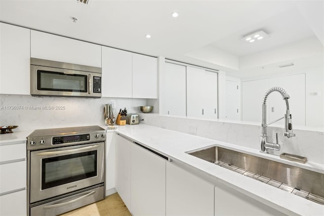 kitchen with stainless steel appliances, a raised ceiling, sink, and white cabinets