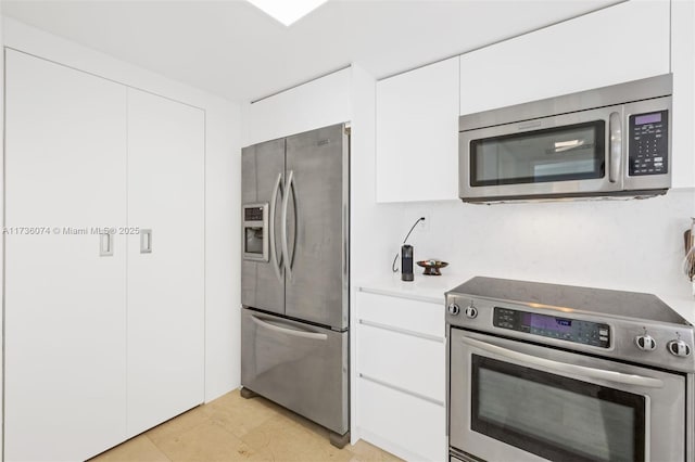 kitchen with appliances with stainless steel finishes, light tile patterned floors, and white cabinets