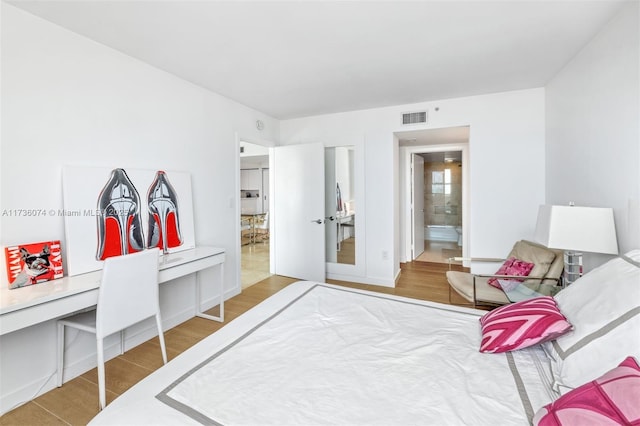 bedroom featuring hardwood / wood-style flooring and ensuite bathroom