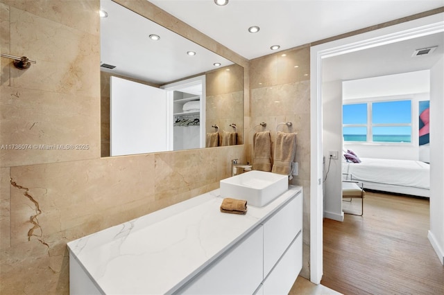 bathroom featuring vanity, hardwood / wood-style flooring, and tile walls