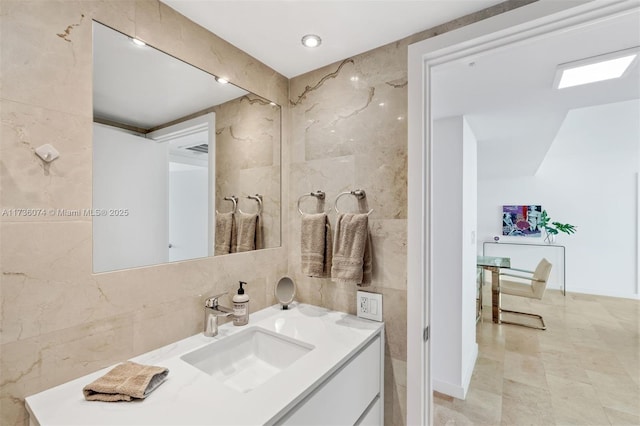 bathroom with vanity and tile walls