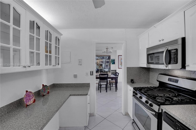 kitchen featuring appliances with stainless steel finishes, white cabinetry, tasteful backsplash, a textured ceiling, and light tile patterned flooring