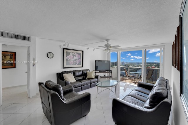 living room featuring light tile patterned flooring, floor to ceiling windows, rail lighting, and a textured ceiling