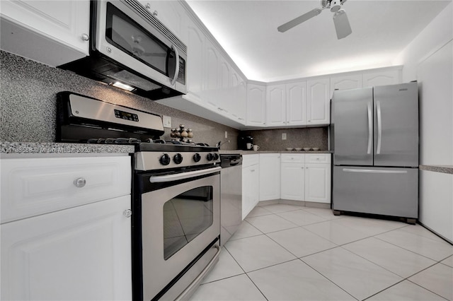 kitchen with light tile patterned floors, ceiling fan, appliances with stainless steel finishes, white cabinetry, and backsplash