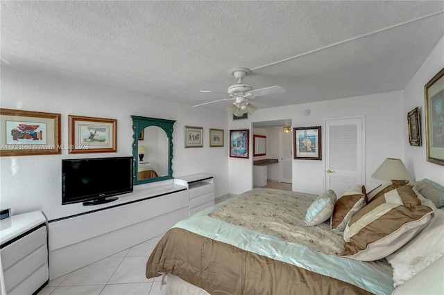 tiled bedroom with ceiling fan, a textured ceiling, and a closet