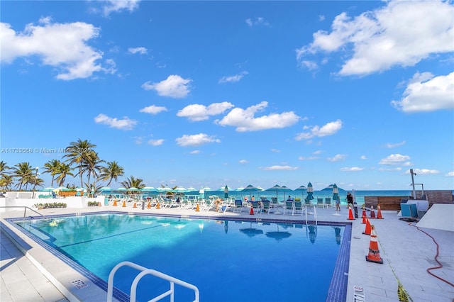 view of pool featuring a patio and a water view