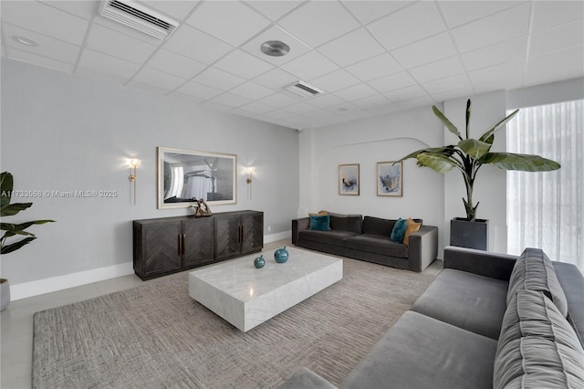 living room with a paneled ceiling and light tile patterned floors