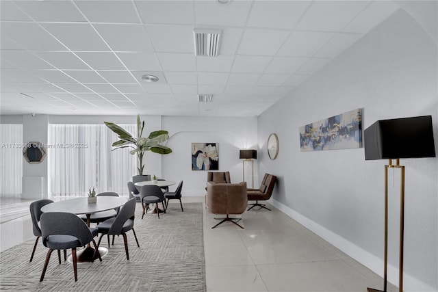 tiled dining room featuring a drop ceiling