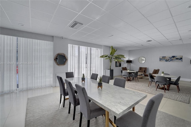 dining space with light tile patterned flooring and a paneled ceiling