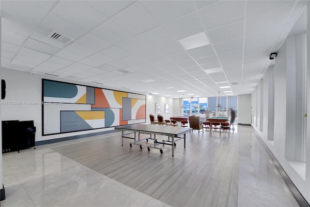 rec room featuring a paneled ceiling and floor to ceiling windows