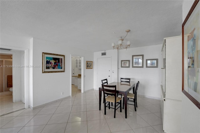 dining space featuring light tile patterned flooring, a chandelier, and a textured ceiling