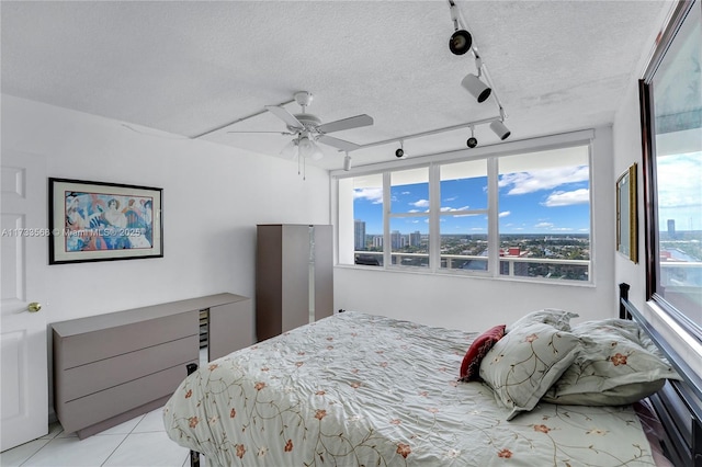 bedroom featuring ceiling fan, a textured ceiling, and light tile patterned floors