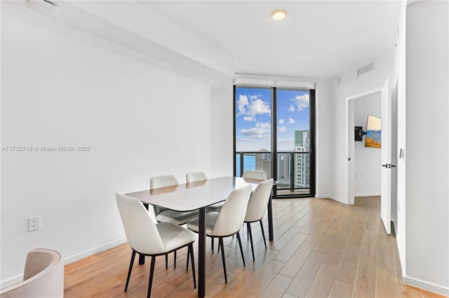 dining space featuring expansive windows and light wood-type flooring