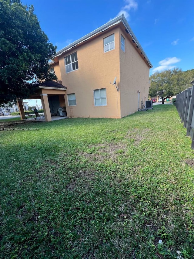 back of property featuring cooling unit and a lawn