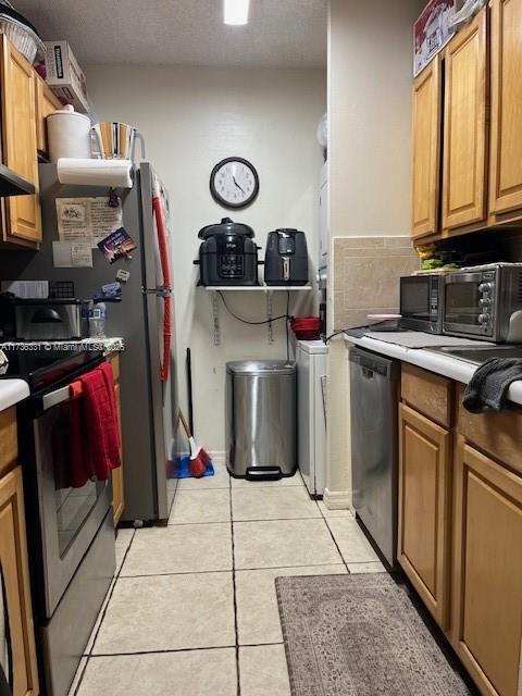 kitchen with appliances with stainless steel finishes, light tile patterned floors, and a textured ceiling