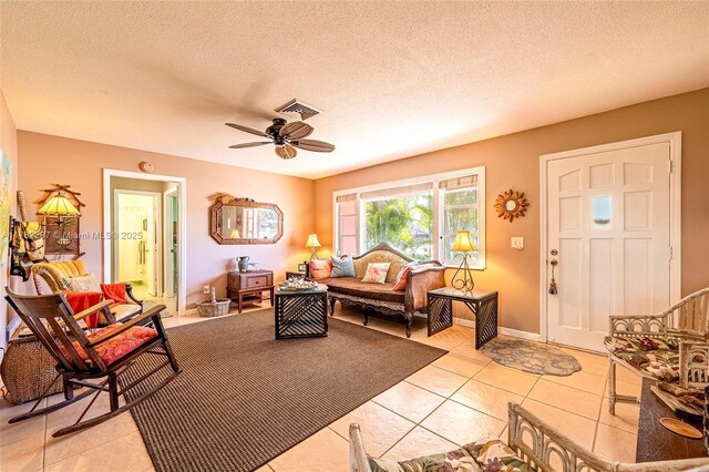 living room with ceiling fan, light tile patterned floors, and a textured ceiling