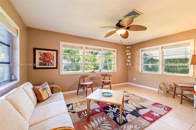 living room featuring ceiling fan, a textured ceiling, and light tile patterned floors