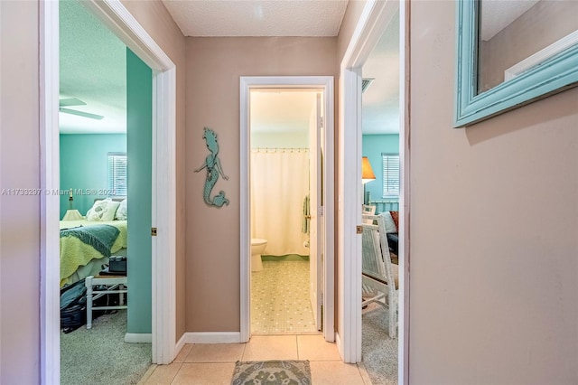 hall featuring a textured ceiling and light tile patterned floors