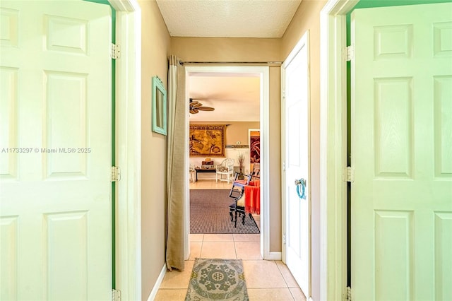 hall featuring light tile patterned flooring and a textured ceiling