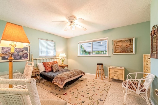 carpeted bedroom featuring ceiling fan and a textured ceiling