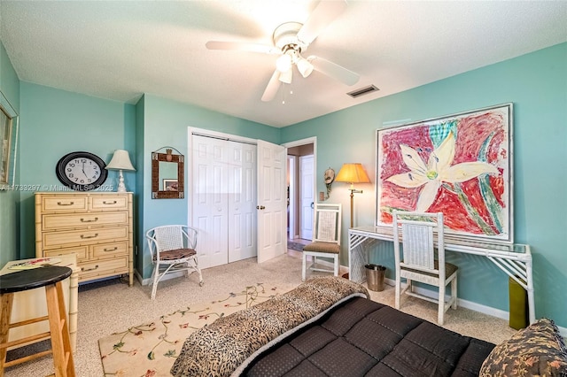 bedroom featuring ceiling fan, light colored carpet, a closet, and a textured ceiling