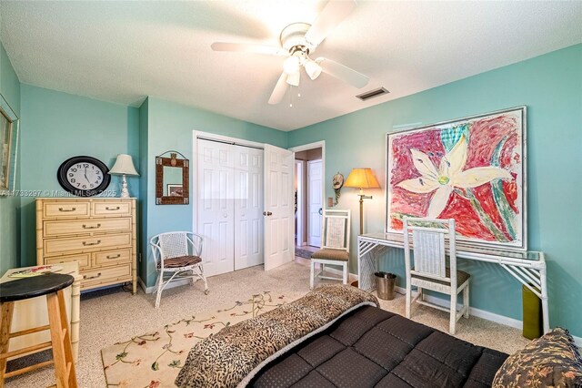 bedroom featuring ceiling fan, light colored carpet, a closet, and a textured ceiling