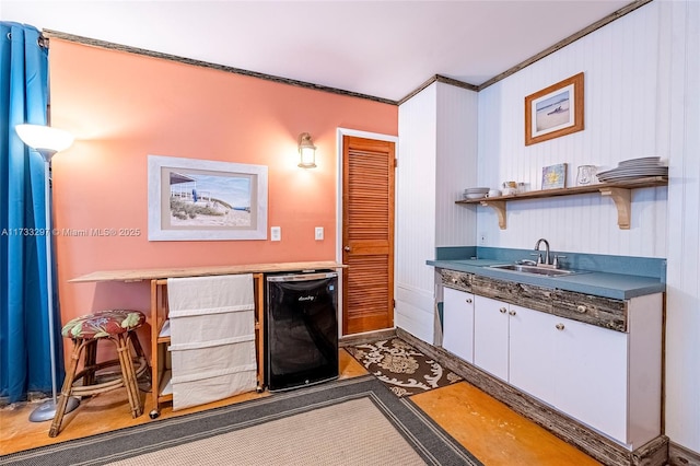 kitchen with sink, ornamental molding, and beverage cooler