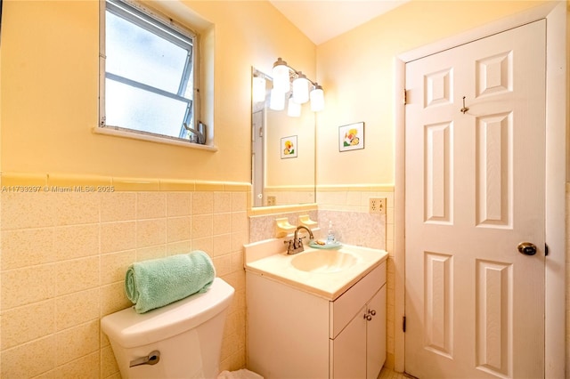 bathroom featuring vanity, toilet, and tile walls