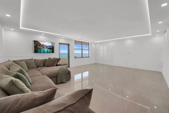 living room featuring a tray ceiling and a water view