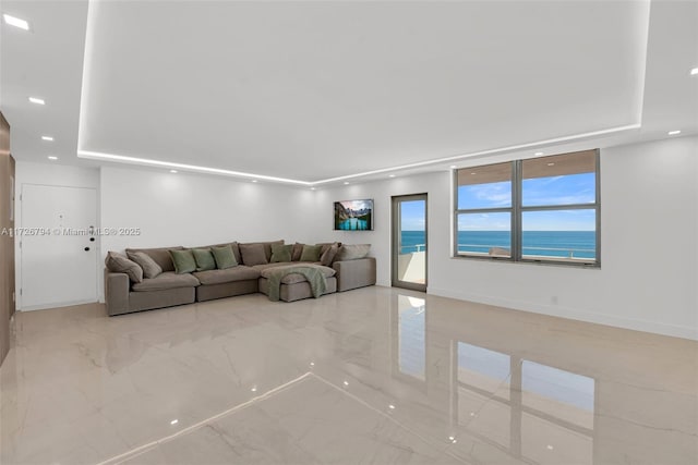 living room with a water view and a tray ceiling