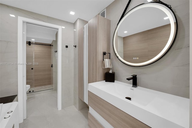 bathroom featuring vanity, tiled shower, tile walls, and toilet