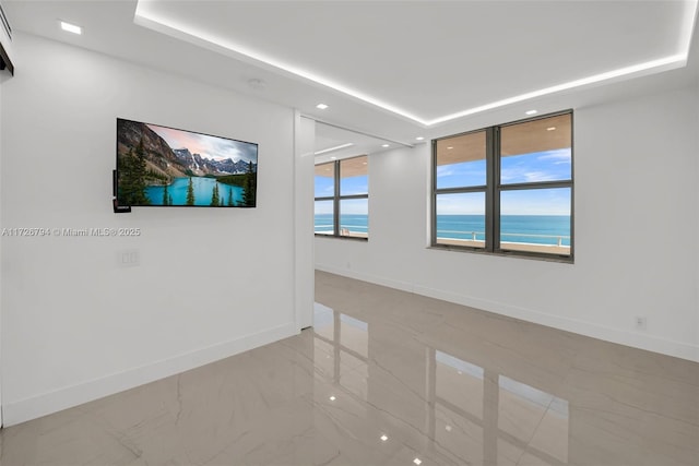 unfurnished room with a wealth of natural light and a raised ceiling