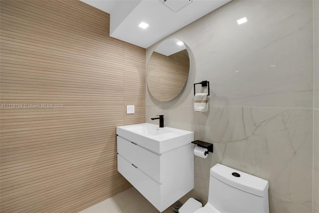 bathroom featuring vanity, tile walls, and toilet