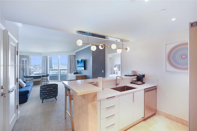 kitchen featuring dishwashing machine, sink, pendant lighting, a breakfast bar area, and white cabinets