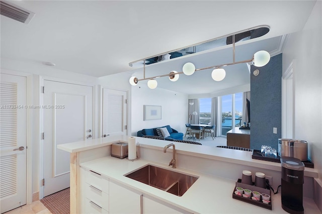 kitchen with sink, hanging light fixtures, and white cabinets