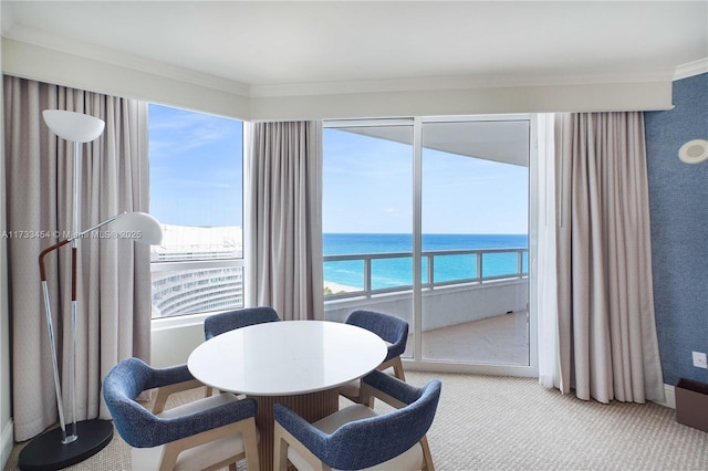 carpeted dining area featuring a water view and crown molding