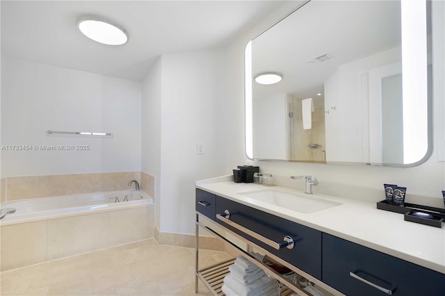 bathroom with tile patterned flooring, vanity, and tiled bath